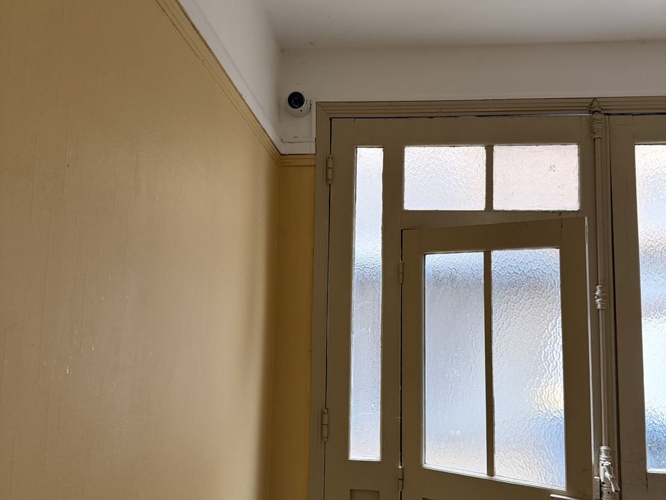 Caméra dôme au plafond d'un couloir, au-dessus d'une porte vitrée