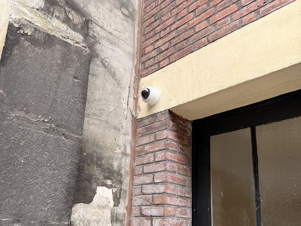 Caméra dôme fixée à l'angle d'une façade en brique, au-dessus d'une vitrine