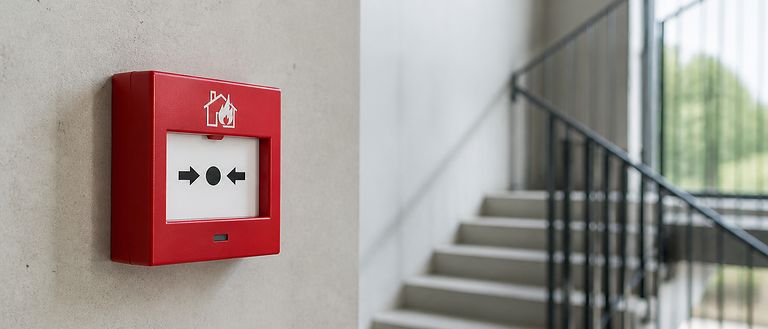 Déclencheur manuel d'alarme incendie rouge dans une cage d'escalier