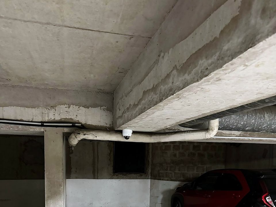Caméra dôme fixée sous une poutre dans un parking souterrain