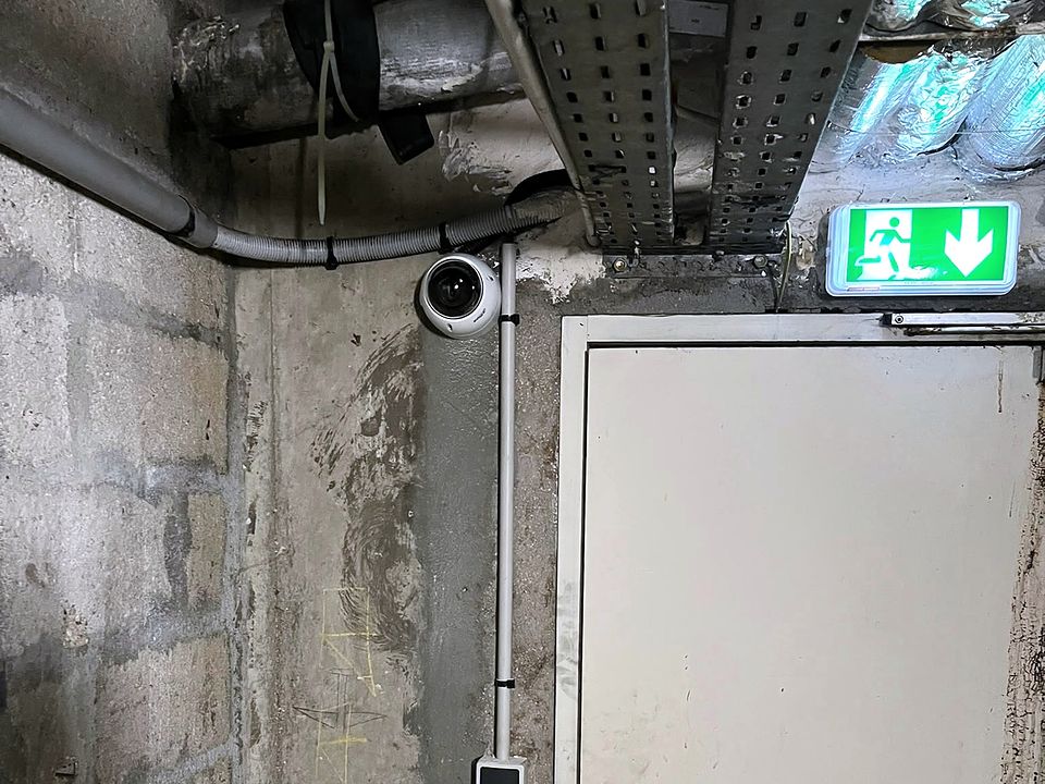 Caméra dôme dans un local en sous-sol, près d'une porte coupe-feu